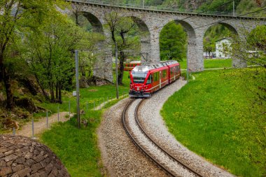 İlkbaharda İsviçre Alpleri 'nin yakınlarındaki Brüksel yakınlarındaki dairesel viyadük köprüsündeki kırmızı tren.