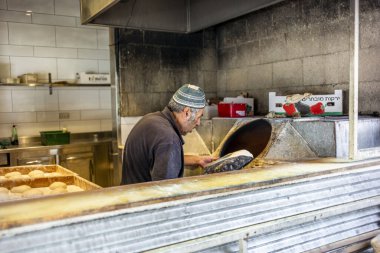 JERUSALEM; ISRAEL - 24 Haziran 2021: Geleneksel bir fırında İsrail laffa ekmeği pişiren bir fırıncı