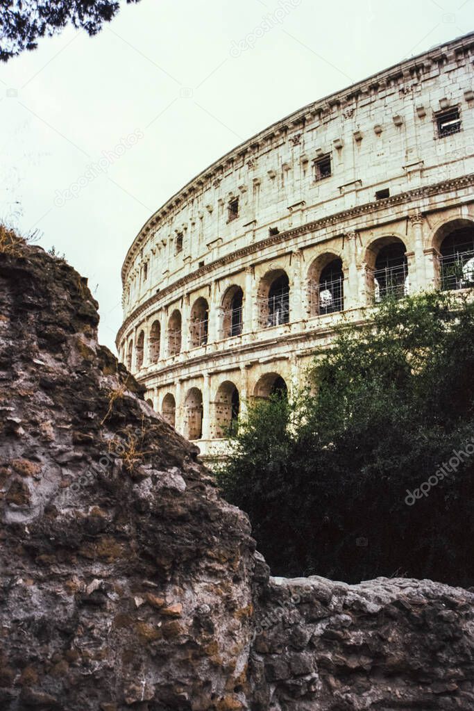 Details of the Colosseum amphitheatre in Rome with a stone out of focus in the foreground, shot with analogue film technique