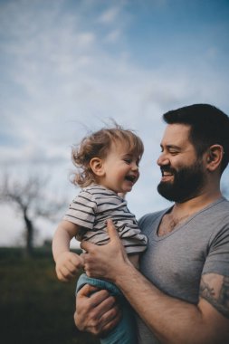 Yürüyüş sırasında babasının ellerinde mutlu bir çocuk..