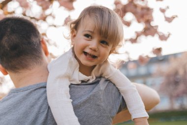 Gülümseyen oğlunu boynunda taşıyan bir baba..