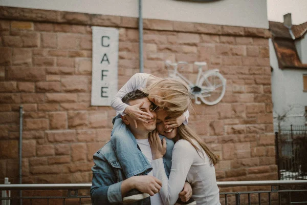 Молода щаслива сім'я стоїть на тлі стіни з вивіскою кафе . — стокове фото
