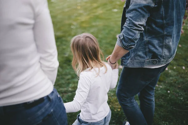 Ebeveynler yürüyüş için kızlarının ellerini tutarlar..