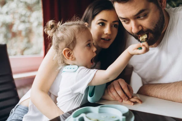 Küçük çocuk babasını kaşıkla besliyor..