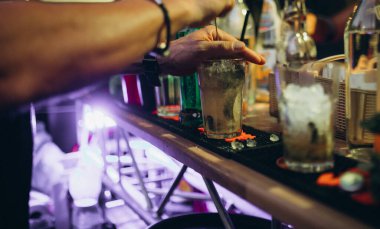 Bir adam kokteyl barında kokteyl yapar..
