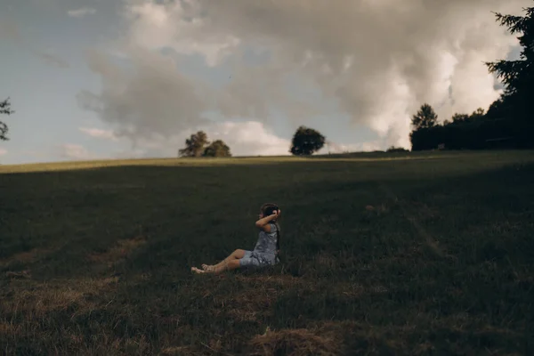 Mavi gökyüzünün arka planında bir kız oturuyor — Stok fotoğraf