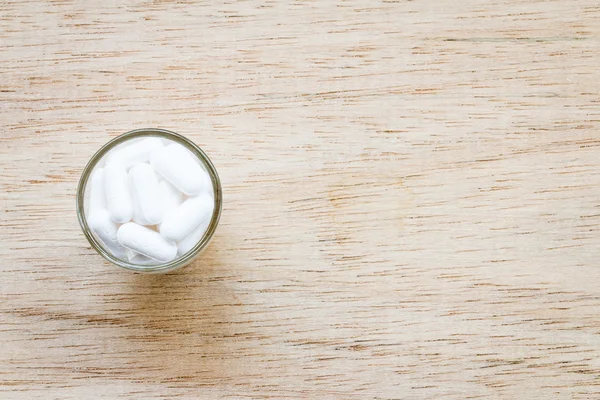 Pastilla blanca en vidrio sobre fondo de madera —  Fotos de Stock