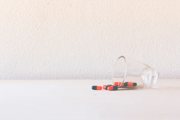 Pille im Glas auf Holzboden und Betonhintergrund — Stockfoto