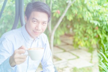 Bahçedeki kahve zevk. Genç adam elinde bir fincan ho