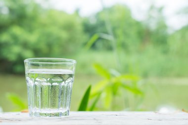 Göl arka plan ile ahşap masa üzerine soğuk su 