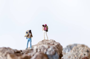 Minyatür insanlar, sırt çantalı yürüyüşçüler dağın tepesinde duruyor, macera konsepti.