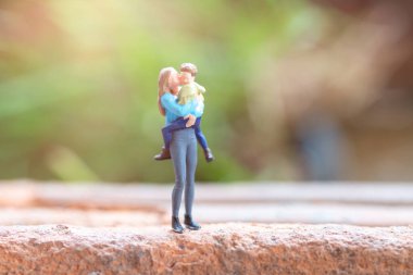 Minyatür insanlar, anne kucağında tatlı bebeğiyle mutlu anneler günü konsepti.