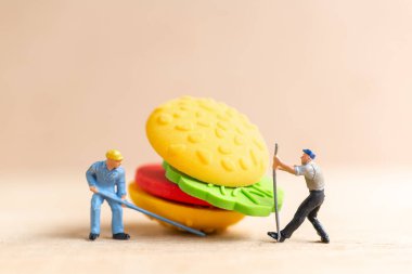 Miniature people workers make A hamburger , fast food and junk food concept.