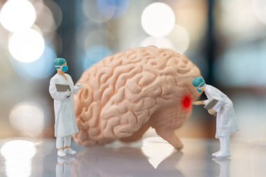 Minyatür insanlar doktor ve hemşire insan beyni, bilim ve tıp kavramını inceliyor ve tartışıyor.