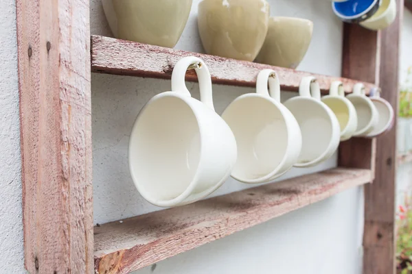 木製の棚にぶら下がっている白いコーヒー カップ — ストック写真