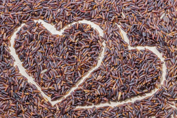 Close-up heart shape brown rice on wooden background — Stock Photo, Image