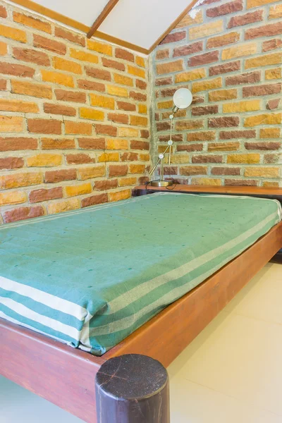 Een single bed naast bakstenen muur achtergrond — Stockfoto