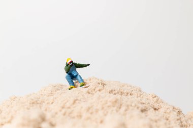 Küçük bir snowboardcu figürü kum tepeciklerinin üzerinde geziyor, eğlenceli açık hava macera titreşimleri ile yaratıcı makro konsept..