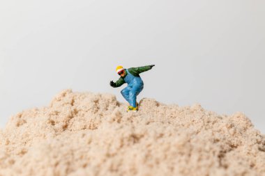 Küçük bir snowboardcu figürü kum tepeciklerinin üzerinde geziyor, eğlenceli açık hava macera titreşimleri ile yaratıcı makro konsept..