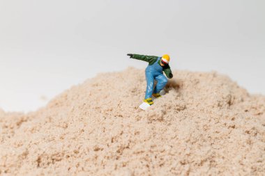 Küçük bir snowboardcu figürü kum tepeciklerinin üzerinde geziyor, eğlenceli açık hava macera titreşimleri ile yaratıcı makro konsept..