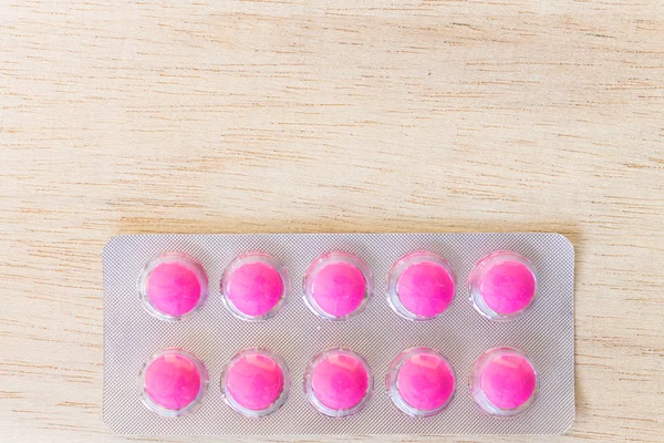 Розовые таблетки в блистерной упаковке на деревянном фоне — стоковое фото
