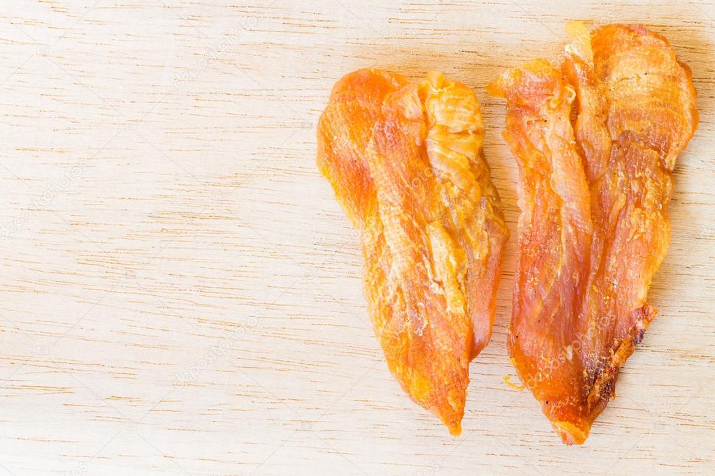 Dried chicken jerky for dogs on wooden background