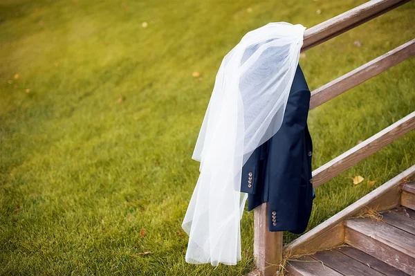 veil of the bride and groom\'s jacket on wooden stairs