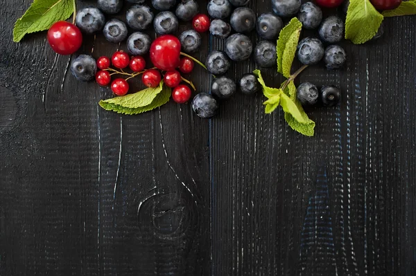 Fresh berries and mint on rustic dark wooden background. vintage background — Stock Photo, Image