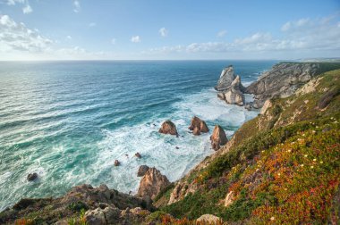 Atlantik Okyanusu manzaralı güzel bir ufuk, kumlu bir sahil, gün doğumunda kayalar ve dalgalar. Ursa Sahili, Sintra, Portekiz