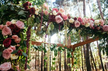 Çiçeklerle süslenmiş yeşil ormanda düğün kemeri.