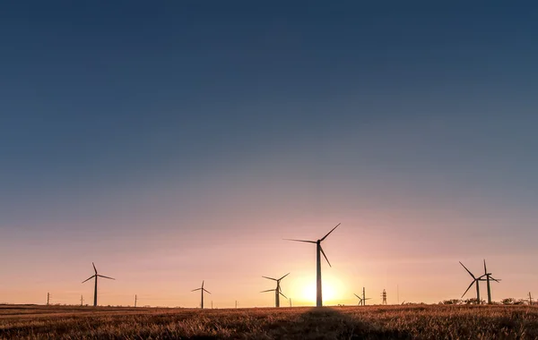 Silhueta de um moinho de vento em um campo rural no pôr-do-sol, bac natural — Fotografia de Stock