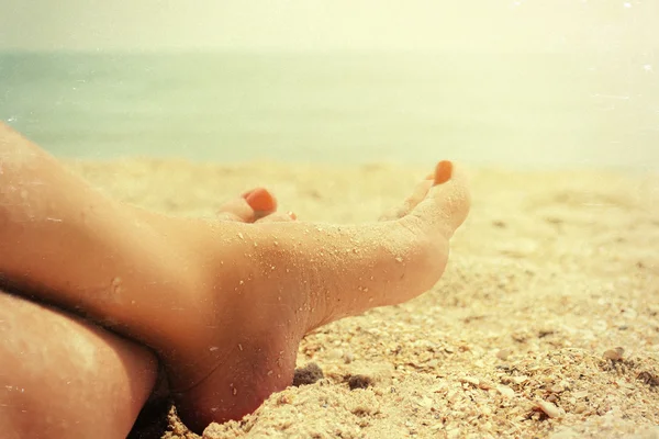 Piedi di primo piano wooman rilassante sulla spiaggia dell'oceano, vintage sfondo estivo — Foto Stock