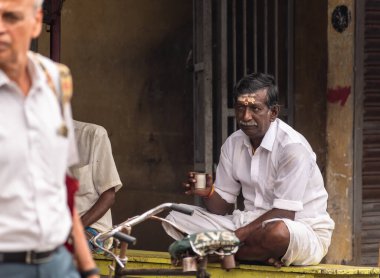 Mayiladuthurai, Tamil Nadu, Hindistan - Şubat 2020: Beyaz giysili ve alnında külden şeritler olan yaşlı bir Hintli çay içiyor..