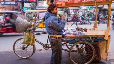 Malda, Batı Bengal, Hindistan - Ocak 2018: Tekerlekli arabası ile bir Hintli sokak satıcısı mallarını bir mikrofona açıkladı.