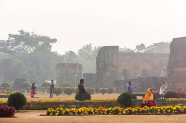 Malda, Batı Bengal, Hindistan - Ocak 2018: Pandua köyündeki antik Adina Mescidi camisinin sisli kalıntılarının etrafındaki bahçelerde turistler.