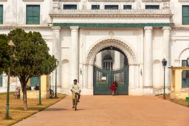 Murshidabad, Batı Bengal, Hindistan - Ocak 2018: Murshidabad 'daki Nizamat İmambara' nın antik geçidine giden yolda bisiklet süren bir adam.