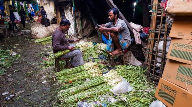 Kolkata, Batı Bengal, Hindistan - Ocak 2018: Kolkata kentindeki Mullick Ghat çiçek pazarında yol kenarında yeşil yapraklar satan sokak satıcıları.