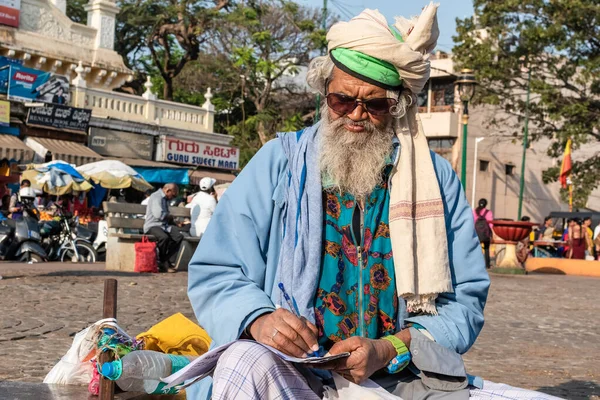 インド カルナータカ州ミスル2019年1月 サングラスをかけて外に座って執筆する老人の肖像 — ストック写真