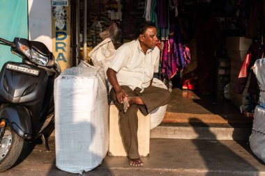 Mysore, Karnataka, Hindistan - Ocak 2019: Şehrin sokaklarındaki bir dükkanın önünde oturan Hintli bir adamın samimi bir portresi.