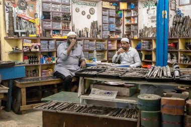 Bangalore, Karnataka, Hindistan - Ocak 2019: Bir hırdavatçıda iki Müslüman esnaf, şehirdeki KR pazarında metal, fındık, cıvata ve diğer endüstriyel ekipman satıyorlar.