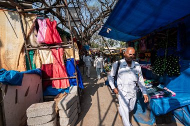 Bangalore, Karnataka, Hindistan - Ocak 2019: Bengaluru 'nun KR Pazarı bölgesinde dükkan ve tezgahlarla dolu bir kaldırımda yürüyen Hintli adam.