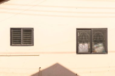 Mangalore, Hindistan - 18 Ocak 2023: Bej duvarlı eski bir kır evinin kare pencereleri.