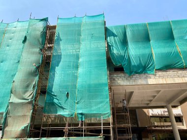 Mangalore, Hindistan - 16 Ocak 2023: Bir inşaat sahasının yeşil güvenlik ağları ve iskelesi.