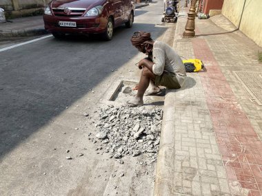 Mangalore, Hindistan - 16 Ocak 2023: Sokaktaki beton blokları tamir eden bir işçi.