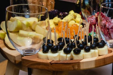 Kavrulmuş ahşap tezgahta peynirden ve siyah zeytinden yapılmış kanepeler..