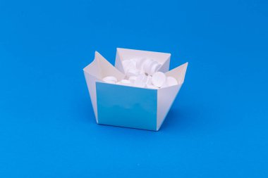 Mavi arkaplanda tabletleri olan beyaz kutu