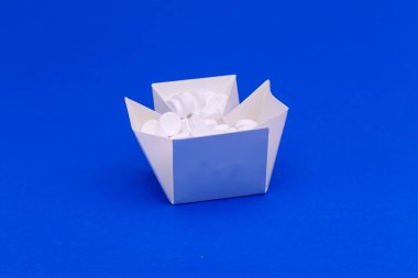 Mavi arkaplanda tabletleri olan beyaz kutu