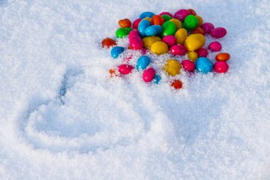 Karda çok renkli kalp şekilli şekerler. Karda şeker. Sevgililer Günü.
