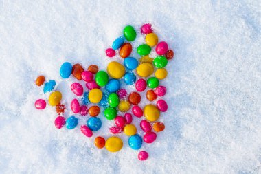 Karda çok renkli kalp şekilli şekerler. Karda şeker. Sevgililer Günü.