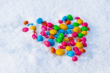 Karda çok renkli kalp şekilli şekerler. Karda şeker. Sevgililer Günü.